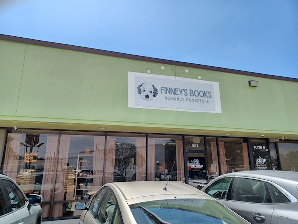 The sign for Finney's books on a green background in a strip mall storefront. 