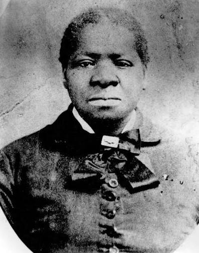 Black and wite photo of Biddy Mason. She faces the camera unsmiling with hair that is either very short or severely pulled back. She wears a black dress with a white collar.
