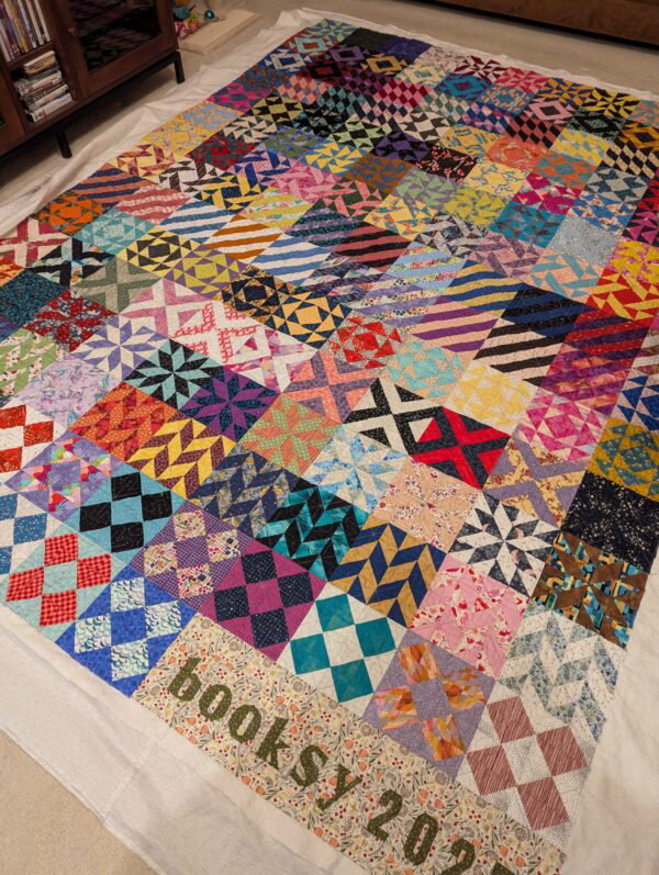 A quilt in myriad colors made of different blocks, with several of the same type of block in different colors in a row, representing the books read that month. New month, new pattern for the block, creating a mosaic effect.