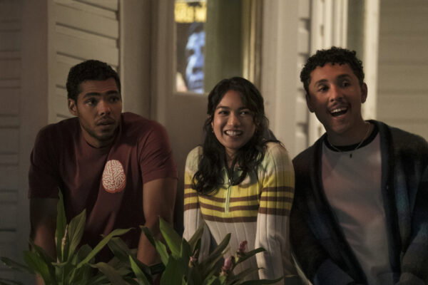 Malcolm, Ahn, and a third man with brown skin are outside looking and smiling at something off screen