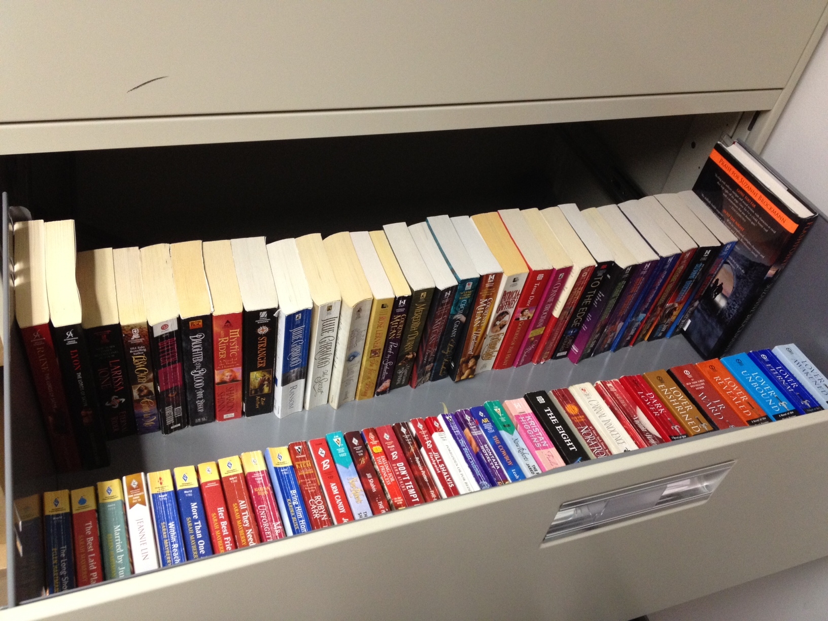 A long desk drawer FILLED with romance novels lined up in order. 